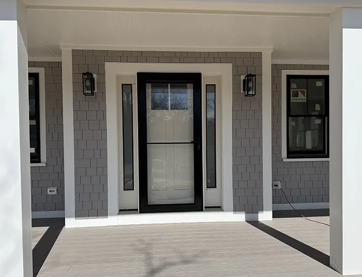 Shingled entry with a new door and black windows